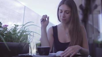 Chica guapa sentada en el café de la calle y escribiendo notas en el cuaderno video