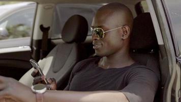 homme africain conduisant une voiture et vérifiant son mobile