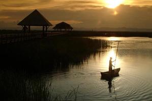 Thai villager punt on lake in Sunset . photo