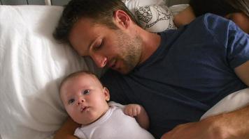 Parents Lying In Bed Cuddling Baby Daughter video