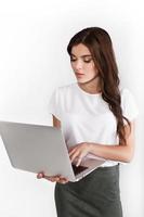 Woman dressed in business style works on laptop on white background photo