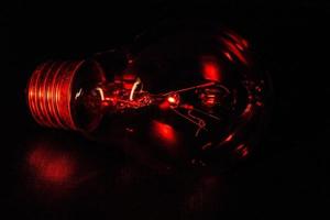 Single light bulb illuminated from the side by red light photo