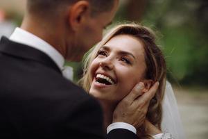 Groom holds bride tender in his arms while she looks at him with love photo