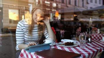 mulher no café usando tablet pc e comendo sobremesa