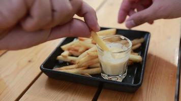 hand takes french fries with cheese dip