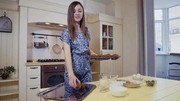 jonge vrouw zet een gebakje in een oven in de keuken, close-up