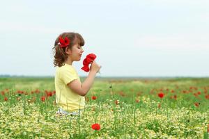 beautiful little girl with poppy flowers on meadow spring season