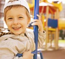 little cute boy on swing outside, playground background