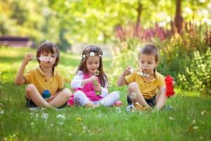 Three children in the park blowing soap bubbles photo