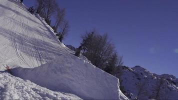 cámara lenta: snowboarder salta sobre pateador, vista de ángulo bajo