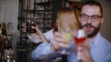 hermosas parejas jóvenes sentadas en un bar y bebiendo vino y cócteles, se divierten y flirtean esta noche video
