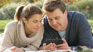 Couple in twenties looking and laughing at social media on smart phone device video