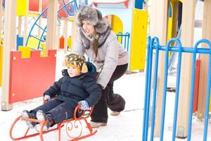 Mother pushing her son on a winter sled photo