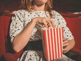Young woman eating popcorn in movie theater photo