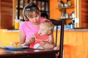 mother feeding little daughter in cafe photo
