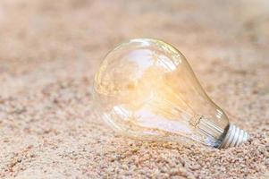 Glowing light bulb in the sand photo