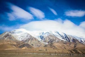 Snow-capped mountains under bright blue clouds photo