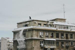 Bucarest, Rumania, 2020 - hombre empujando la nieve del techo
