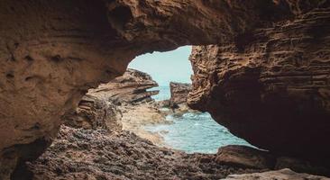 Rocky cave on island during day photo