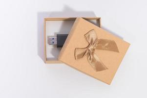 Caja de regalo marrón con unidad flash sobre fondo blanco. foto