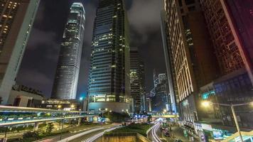Zeitraffer des Geschäftsviertels von Hongkong in der Nacht. Firmengebäude hinten und viel Verkehr über die Hauptstraße zur Hauptverkehrszeit video