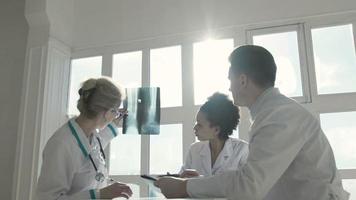 gezondheidszorg, medisch: groep multi-etnische artsen bespreken en kijken naar röntgenfoto's in een kliniek of ziekenhuis.