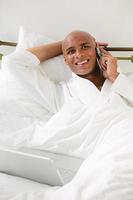 Man in bed with laptop and cellphone photo