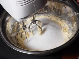 Mezclar mantequilla y azúcar en un tazón con máquina mezcladora foto