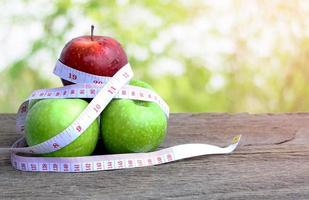 Red apple and green apple with measuring tape photo