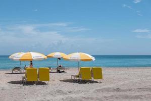 Miami, Florida, 2020 - Beachgoers with yellow umbrella and chairs on beach photo