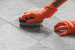Person scrubbing a floor with orange gloves on photo
