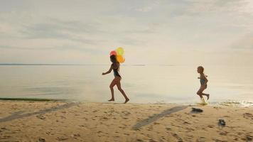 lycklig barndom - två systrar springer runt på varandra på stranden. ha så kul