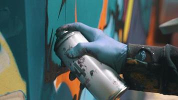 Graffiti artist painting on the wall, interior, close up