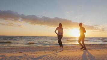 coppia in amore divertendosi sulla spiaggia al tramonto berugegu. l'uomo corre dietro alla ragazza. concetto - la luna di miele, l'energia e la salute video