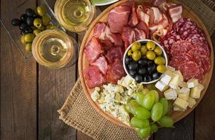 Antipasto catering platter with bacon, jerky, salami, cheese and grapes photo