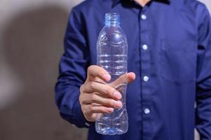 empresario sosteniendo una botella de agua de plástico vacía foto