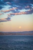 Moon above the ocean at sunset photo