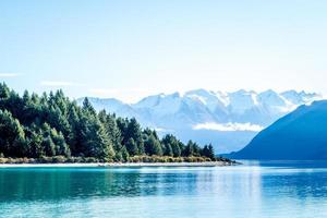 Lake surrounded by trees and snowcapped mountains photo