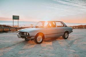 Cape Town, South Africa, 2020 - Grey BMW sedan in front of setting sun photo