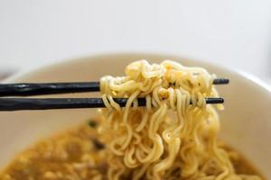 Black wooden chopsticks holding noodles photo
