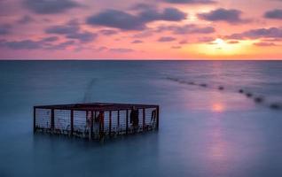 Seascape and Empty Cage at Colorful Sunset photo