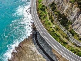 Vista aérea de una carretera cerca de una montaña y el océano. foto