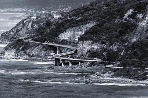 Grayscale of a bridge near the sea photo