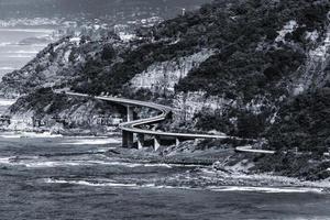 escala de grises de un puente cerca del mar foto