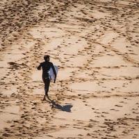 Sydney, Australia, 2020 - Man walking with a surfboard on a beach photo