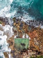 Vista aérea de las olas rompiendo en las rocas foto