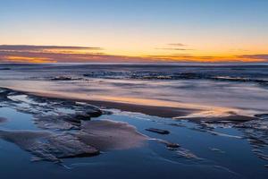 larga exposición de una puesta de sol en una playa foto