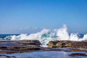 olas chapoteando en las rocas en la playa foto