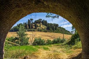 Tuscany, Italy, 2020 - View of a house on a hill through a tunnel photo