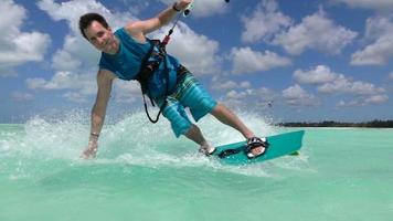 Ralenti: joyeux sourire kite surfeur main faire glisser le kitesurf en mer tropicale